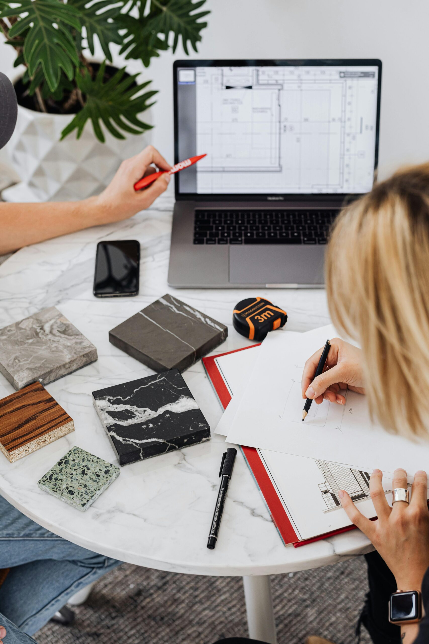 Creative professionals designing interior spaces with laptop and material samples at a modern work table.